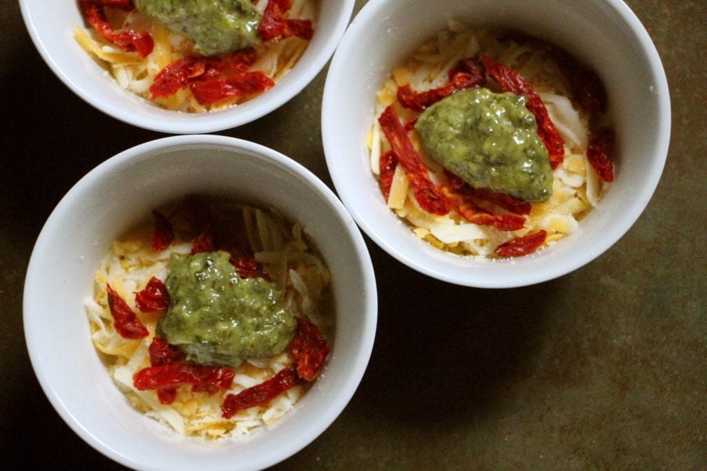 Divide cheese, pesto, and tomatoes among the ramekins